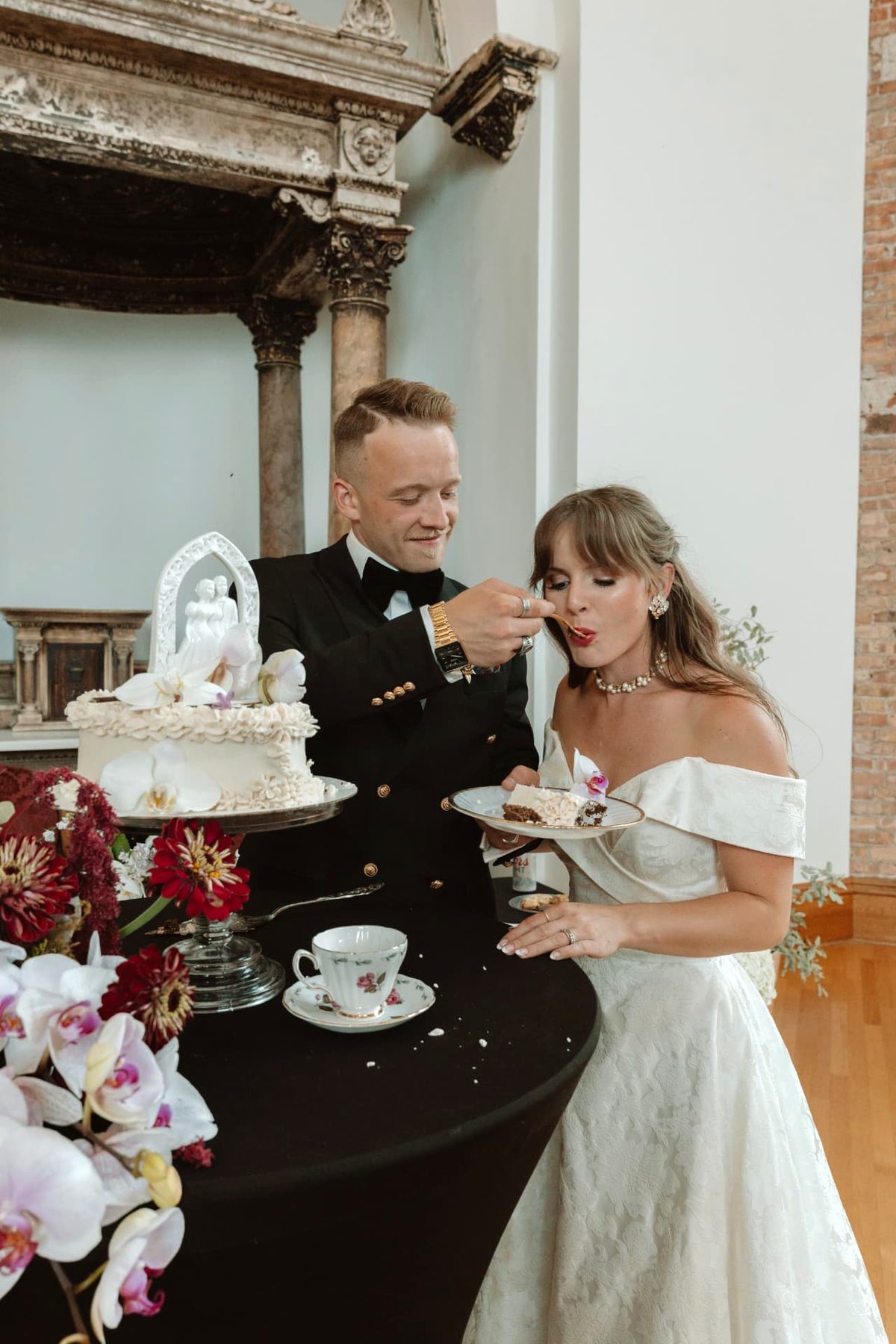 Newlyweds sharing cake beside the orchid sweetheart table