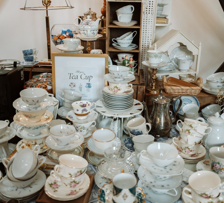 Grandmother's collection of vintage teacups, saucers, and silver teapots with a Fill Your Tea Cup sign